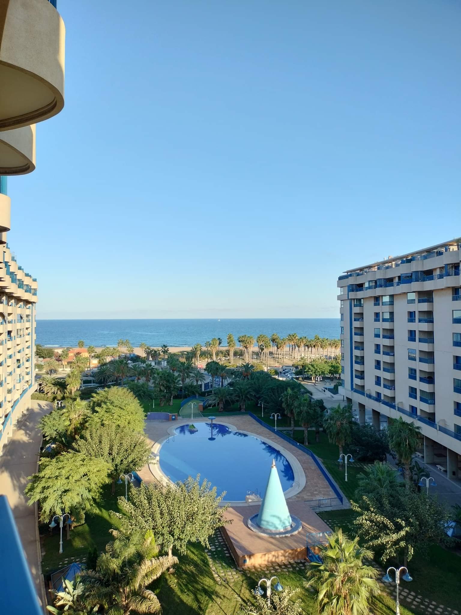 zdjecie basenu, palm i morza, zrobione z balkonu